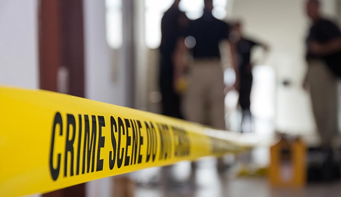 Yellow crime scene tape and police in background