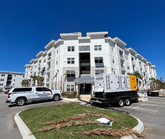 Exterior of a large, modern commercial building with a RestorePro truck and a large industrial generator