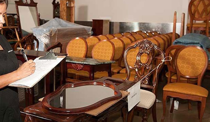 Person taking notes while inspecting furniture including chairs and tables in a room