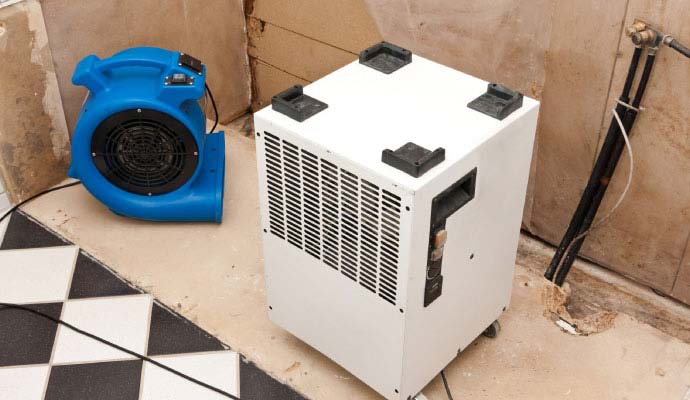 Dehumidifier and blower air mover set up on floor for effective drying