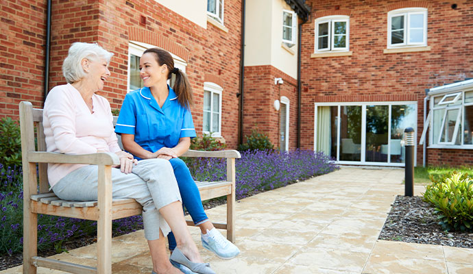 A female nurse and elderly woman sitting on bench