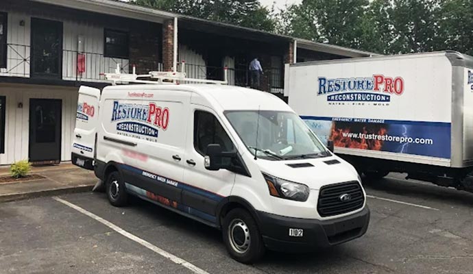 Restore Pro Reconstruction service van and truck parked in front of a building for water fire and mold restoration