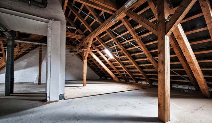 Clean and fully restored empty attic space with wooden rafters and flooring