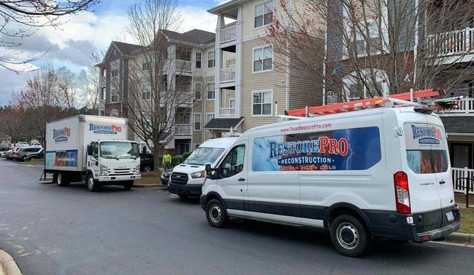RestorePro Reconstruction service trucks parked at an apartment building