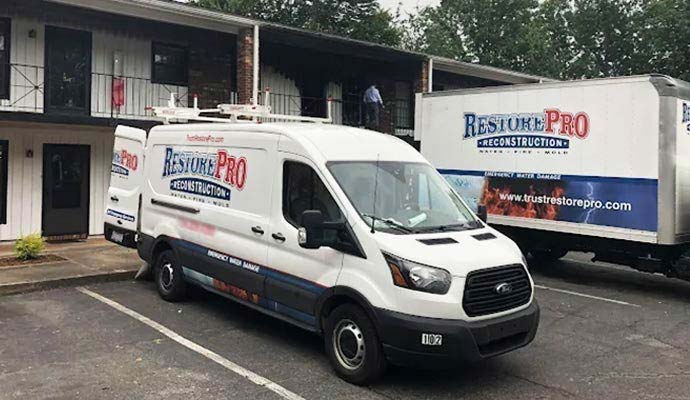 RestorePro Reconstruction service vehicles parked outside a commercial building