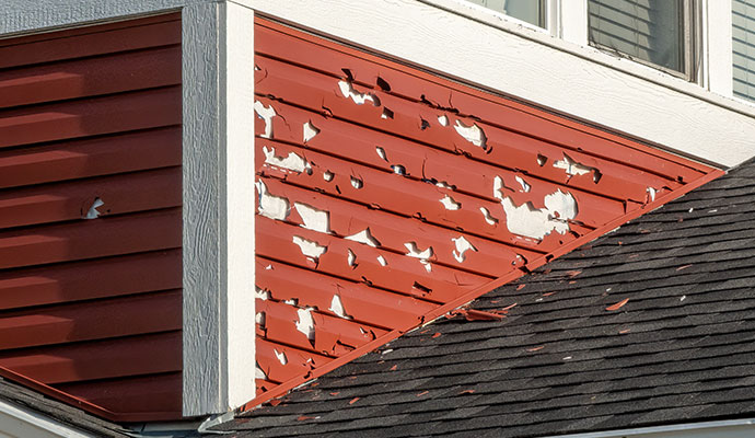 Hail damage impact shattered red vinyl siding