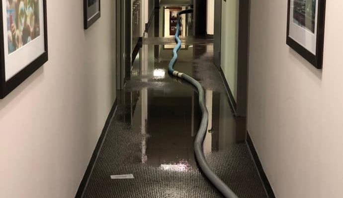 Flooded hallway with water extraction hose