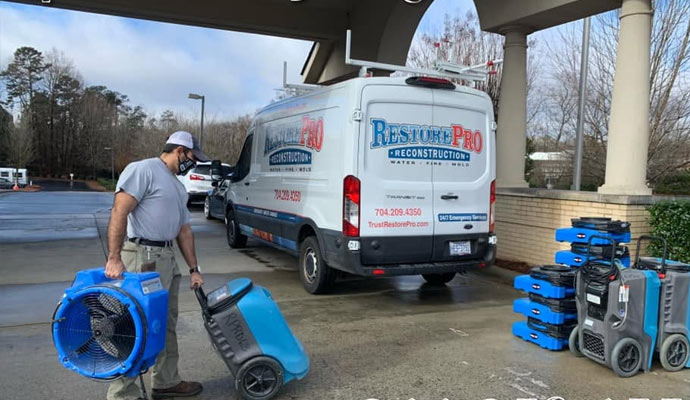 Technician unloading drying equipment from van