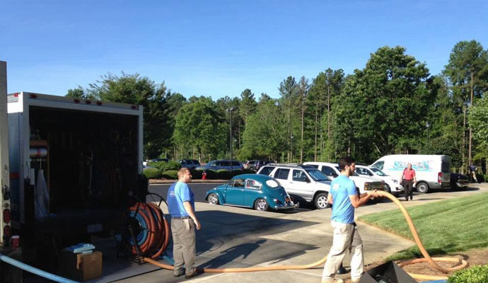 Technicians deploying extraction hose from truck